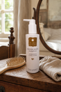 A bottle of Pure Lakes Keratin Silken Shampoo stands on a wooden dresser in a bedroom setting, surrounded by a wooden hairbrush and a beige towel.