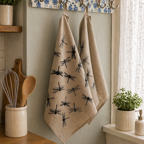 Kitchen towel with black dragonfly pattern hanging on a floral-patterned hook rack.