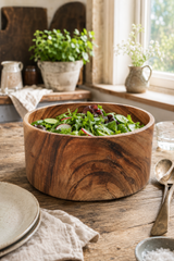 Large Natural Wood Salad & Serving Bowl – 25cm filled with fresh green salad, set on a rustic wooden table in a bright kitchen setting with plates, spoons, and potted plants.