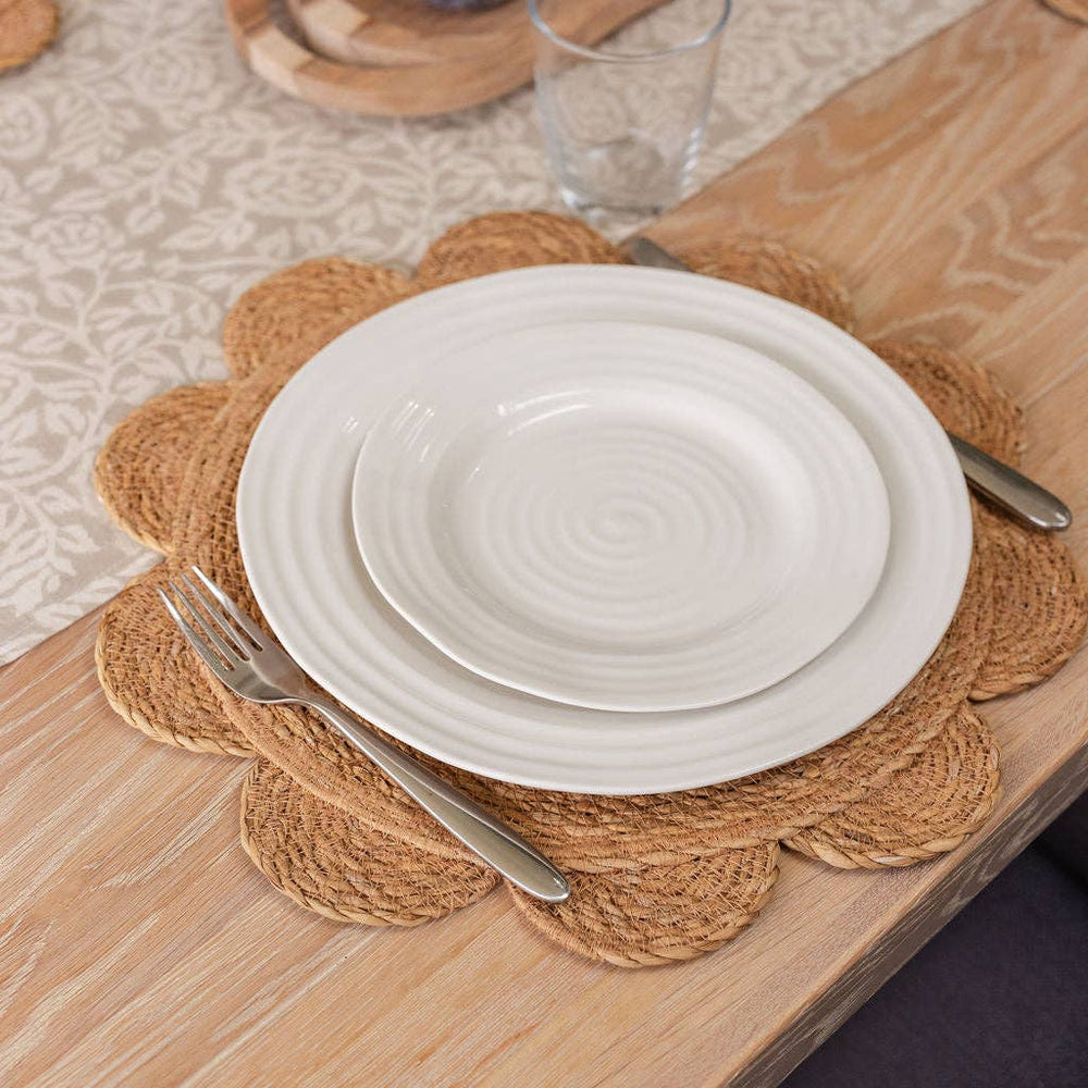 White plates on a woven placemat with a fork on a wooden table.