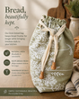 Linen bread bag with floral pattern and wooden drawstring on a kitchen background