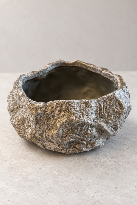 Empty round rock effect ceramic plant pot with an irregular rim and mottled grey, taupe and cream finish.