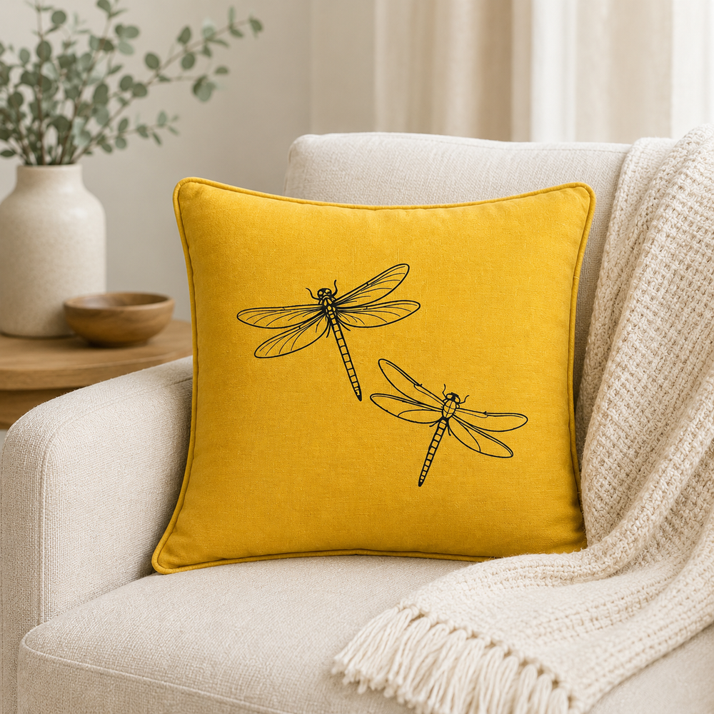 Mustard linen cushion cover with black dragonfly print, styled on a sofa.