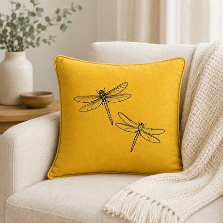 Mustard linen cushion cover with black dragonfly print, styled on a sofa.