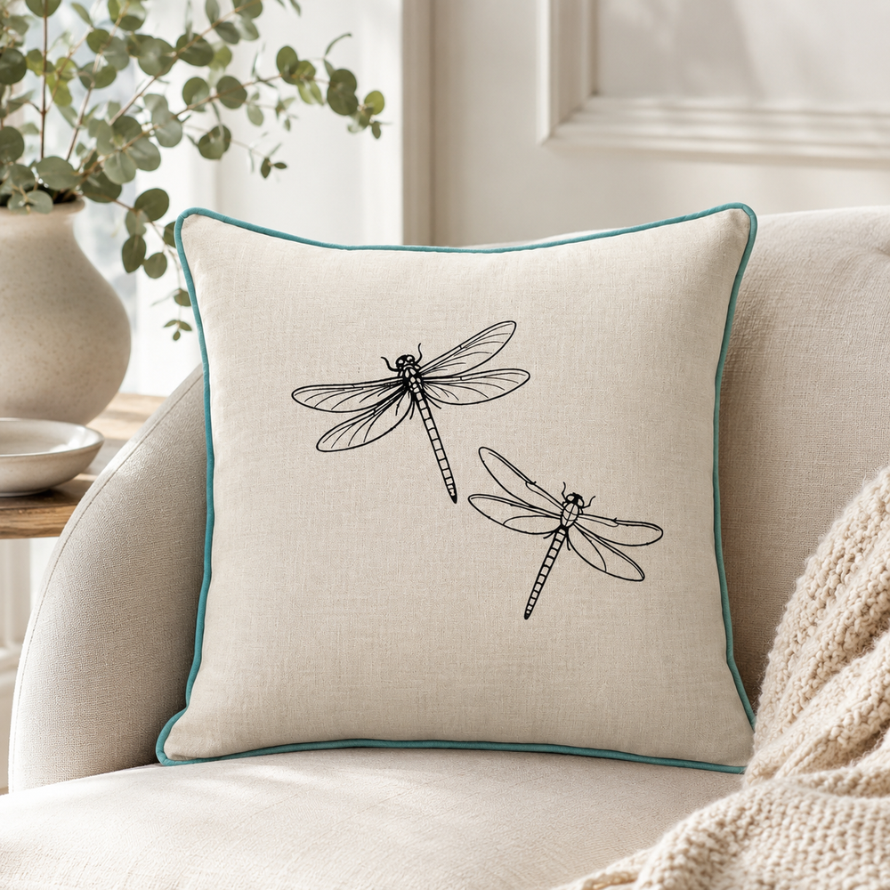 Natural linen cushion cover with black dragonfly print and duck egg piping styled on a sofa.