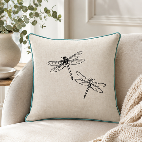 Natural linen cushion cover with black dragonfly print and duck egg piping styled on a sofa.