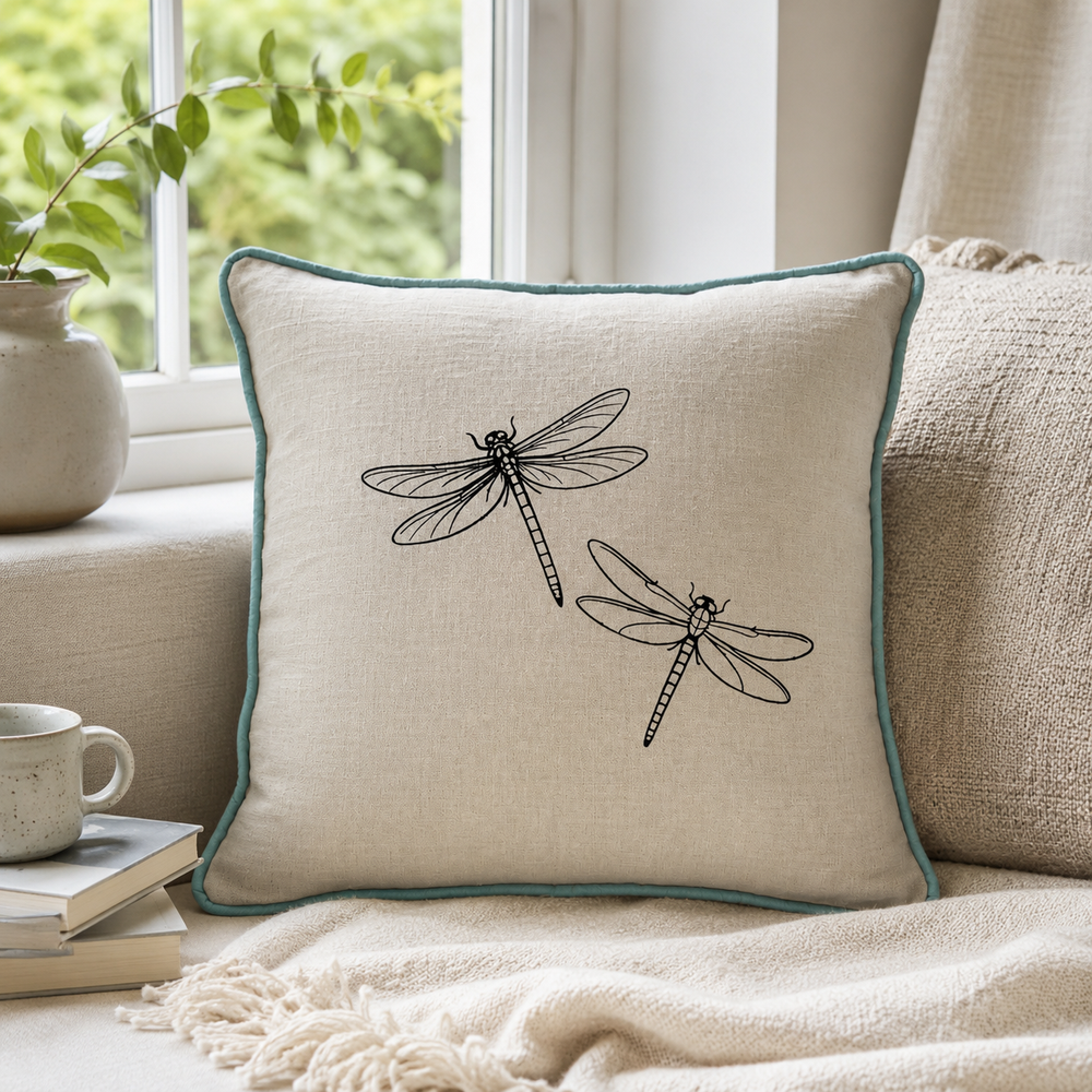 Natural linen cushion cover with black dragonfly print and duck egg piping styled on a window seat.