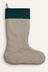 A natural linen Christmas stocking with a dark forest green linen fabric cuff, shown against a plain off-white background.