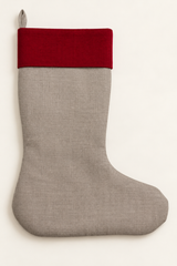 A linen Christmas stocking made of natural linen fabric with a contrasting deep red cuff, shown against a plain off-white background.