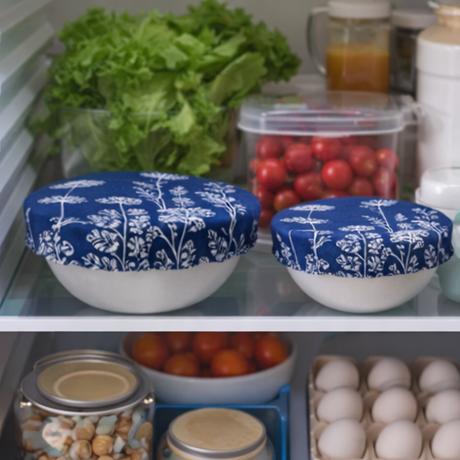 Two white bowls with blue floral lids on a kitchen shelf with vegetables and eggs.
