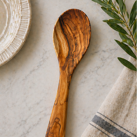Wooden spoon on a marble surface with a plate and towel in the background