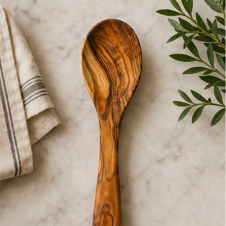 Wooden spoon on a marble surface with a towel and leaves in the background