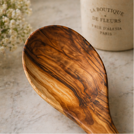 Wooden spoon with a decorative container labeled 'La Boutique de Fleurs' on a marble surface.