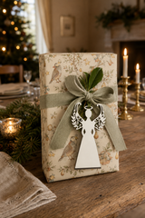 Wide-skirt white angel gift tag on a Partridge in a Pear Tree wrapped present with sage linen ribbon.