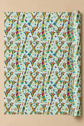 A roll of wrapping paper with a colorful repeating Patchwork Giraffe pattern on a light blue background, displayed against a solid beige backdrop.