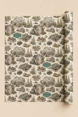 A roll of personalise your own wrapping paper with a detailed garden and greenhouse toile pattern on a warm cream background, displayed against a solid beige backdrop.