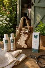 A mini hessian tote bag with a wooden welly boot tag sits on a Wooden surface outdoors with Pure Lake products Foot Gel, Anti-insect lotion and after sun lotion.
