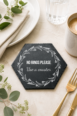 Hexagonal coaster with 'No Rings Please Use a Coaster' text on a table setting with a cup, fork, and greenery.
