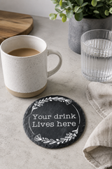 Personalised round slate drinks coaster engraved with wording, made from natural slate with rustic edges.