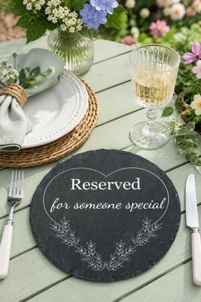 Table setting with a 'Reserved for someone special' placemat, wine glass, and cutlery on a wooden table.