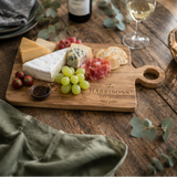 Wooden cutting board with engraved 'the HARRISONS EST. 2022' on a neutral background.