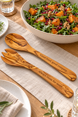 Personalised 30cm olive wood salad servers on oatmeal linen beside a large bowl of rocket, roasted squash, walnuts and pomegranate.