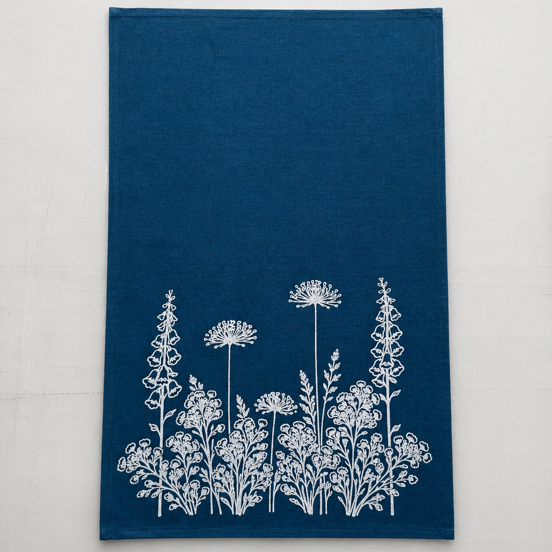 Blue linen tea towel with white floral pattern on a light white background