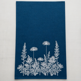 Blue linen tea towel with white floral pattern on a light white background