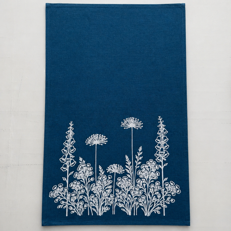Blue linen tea towel with white floral pattern on a light white background