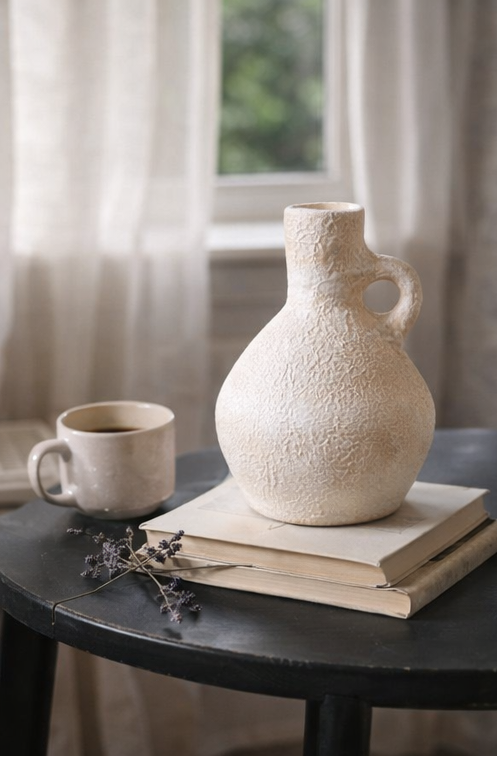 Terracotta vase and mug on books with a window in the background