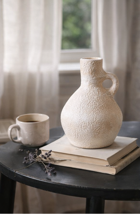 Terracotta vase and mug on books with a window in the background