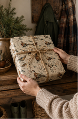Cock and hen pheasants strut, flap and stumble through colourful fairy lights among winter grasses, berries and pine sprigs. A pencil-sketch Christmas wrapping paper with proper British countryside character.