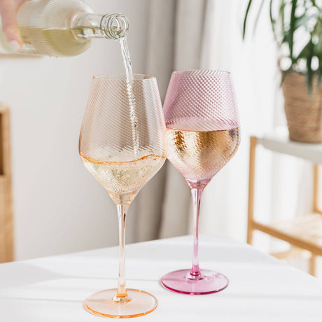 two twist wine glasses being filled 