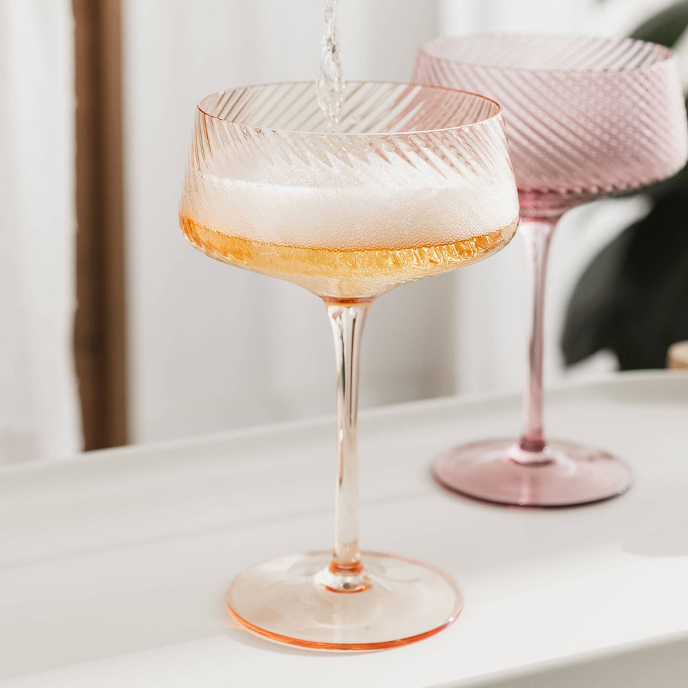 Pink glass with a drink on a white surface
