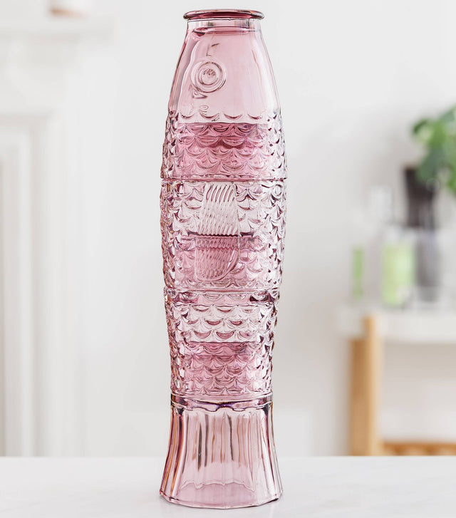 Pink stacking glass set that makes a fish when stacked on a white surface with a blurred background