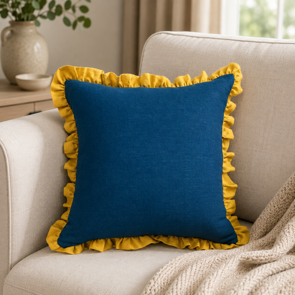 Plain deep blue linen cushion cover with mustard ruffle edge styled on a sofa.
