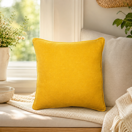 Plain mustard linen cushion cover with piped edge styled on a window seat.