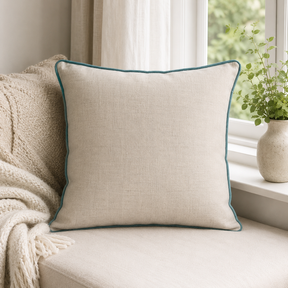 Plain natural linen cushion cover with duck egg piping styled on a window seat.