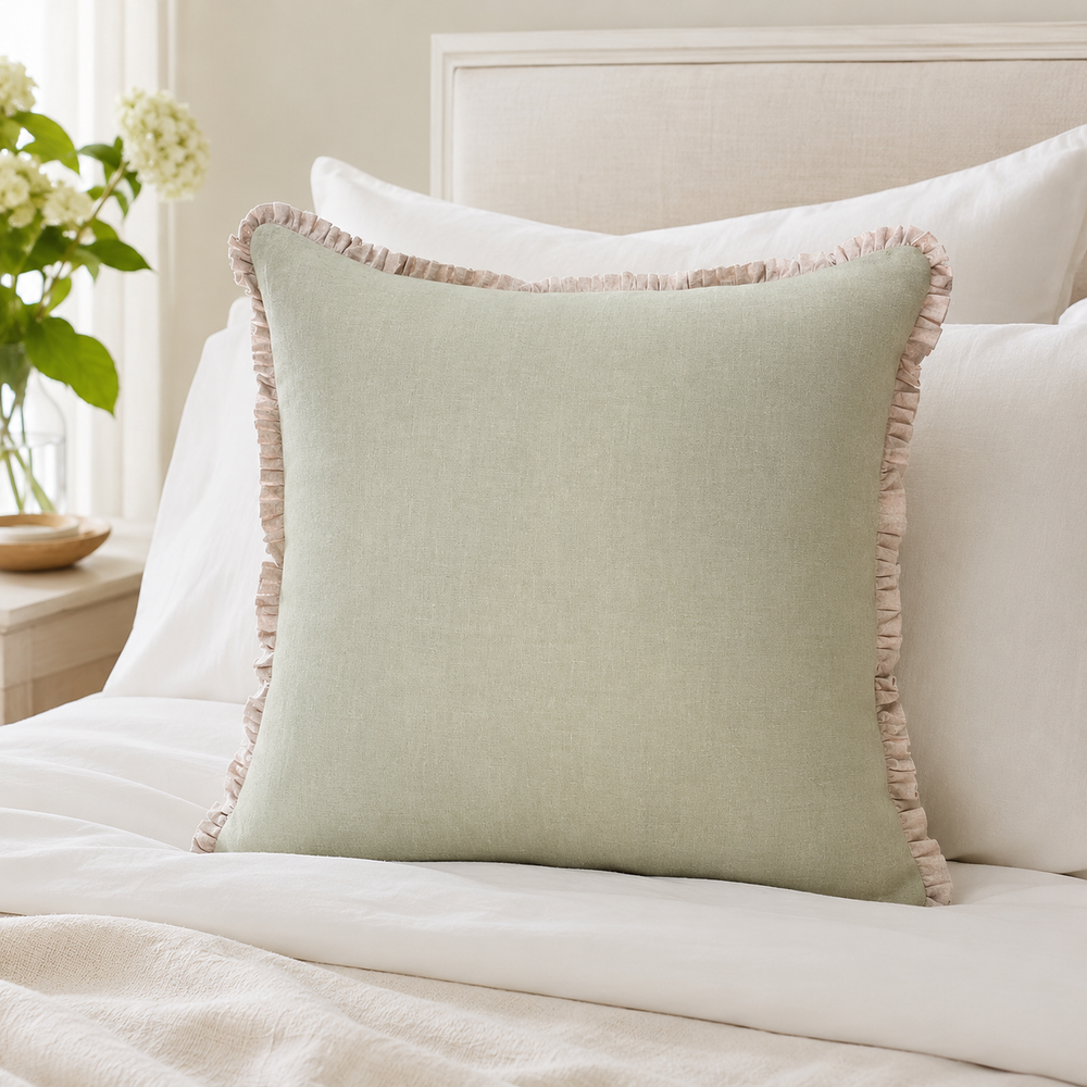 Plain sage linen cushion cover with pale ruffle edge styled on a neutral bed.