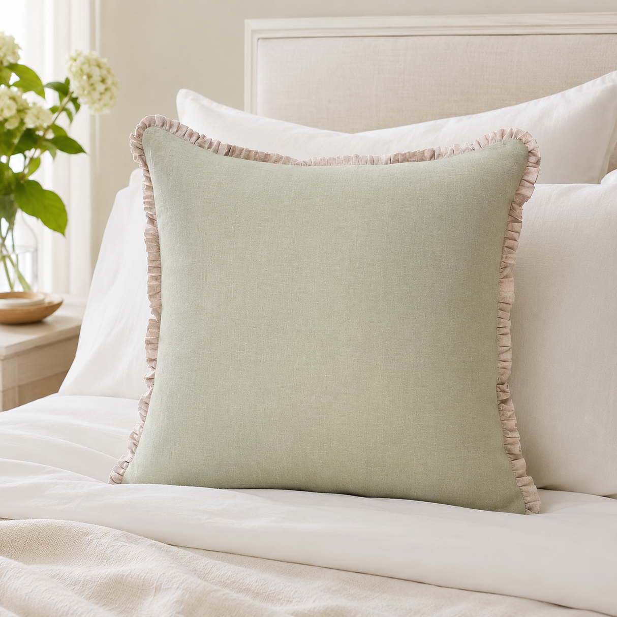 Plain sage linen cushion cover with pale ruffle edge styled on a neutral bed.