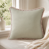 Plain sage linen cushion cover with pale ruffle edge styled on a window seat.