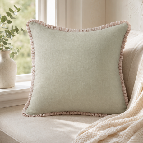Plain sage linen cushion cover with pale ruffle edge styled on a window seat.