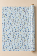 Light blue wrapping paper with a repeating pattern of Power Blue Bonnet Girls Wrapping Paper, shown partially unrolled from a wooden roll against a solid beige background.