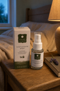 Pure Lakes Sleep & Room Spray bottle and its matching box displayed on a wooden bedside table next to a lit lamp and a book.