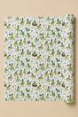 A roll of wrapping paper with a dense pattern of illustrated birds in green, yellow, and brown on an off-white background, shown against a solid beige backdrop.