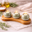 Handcrafted ceramic candle holder set with candles on a wooden holder, surrounded by herbs and a towel.