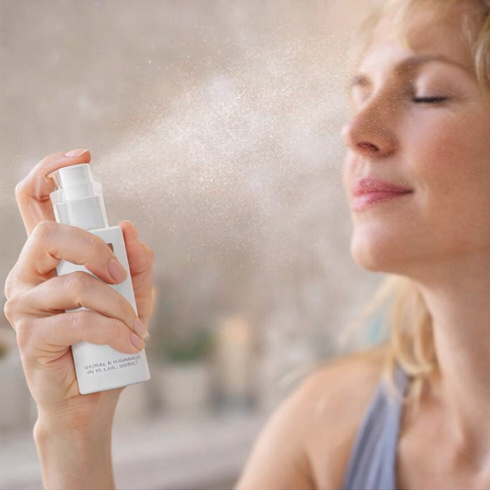 woman using Pure Lakes Flower Water Toner with floral and candle background.