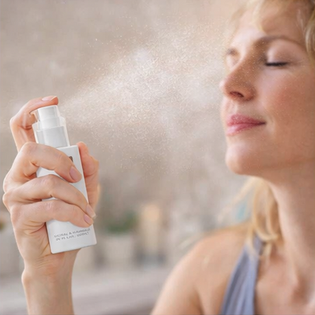 woman using Pure Lakes Flower Water Toner with floral and candle background.