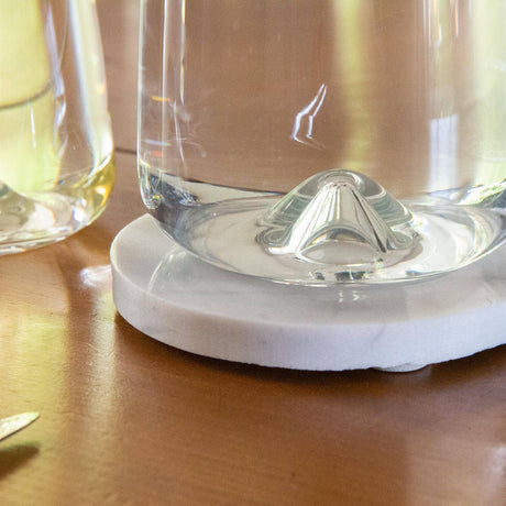 Clear glass with a white marble coaster on a wooden surface