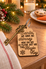 A wooden Santa key tag engraved with the phrase 'Santa, we have no chimney here you see so please just use this Magic Key' and a snowflake, shown on a wooden table with Christmas decorations.